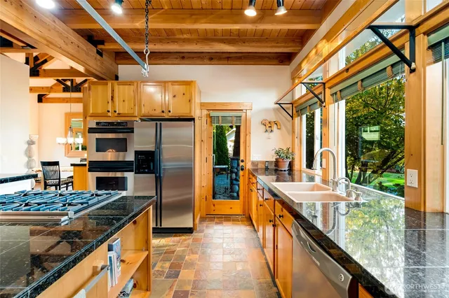 a kitchen with stainless steel appliances granite countertop a sink and a refrigerator