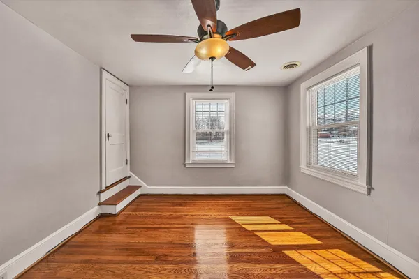 a view of an empty room with window and chandelier fan