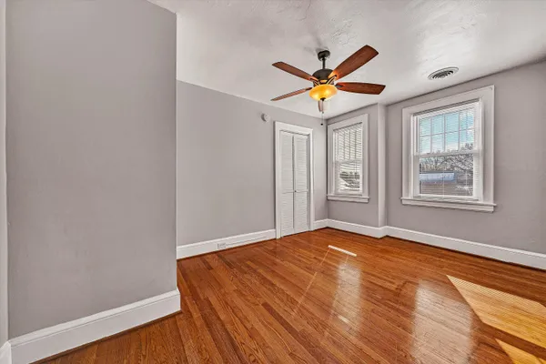 a view of empty room with window and wooden floor