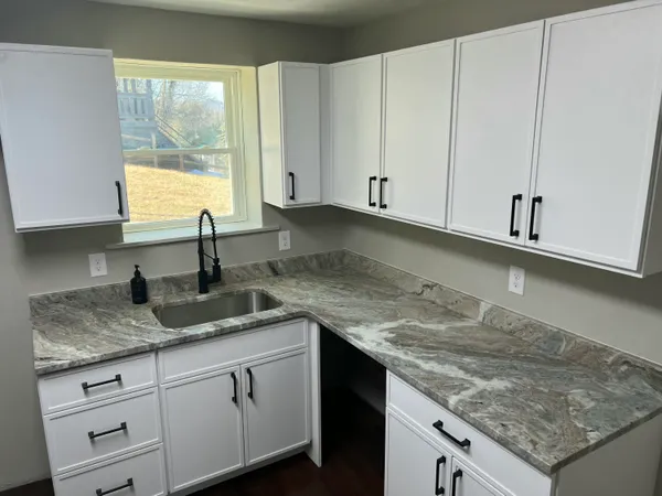 a kitchen with granite countertop a sink and white cabinets