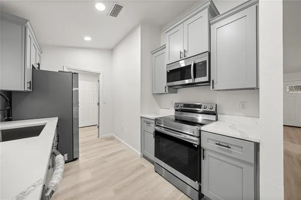 a kitchen with stainless steel appliances white cabinets and a stove top oven
