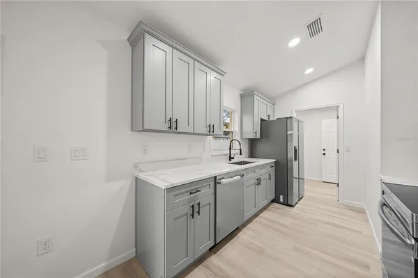 a large white kitchen with stainless steel appliances granite countertop a sink and cabinets with wooden floor