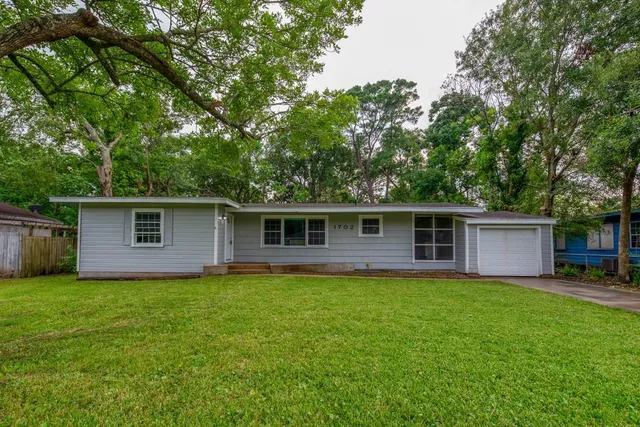 a view of a yard in front of a house with large trees