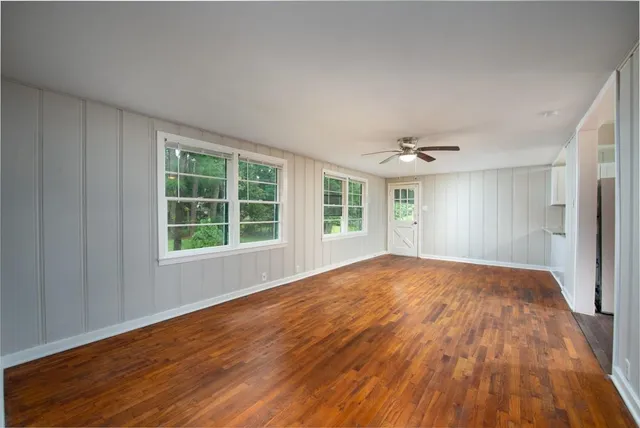 a view of empty room with wooden floor and fan