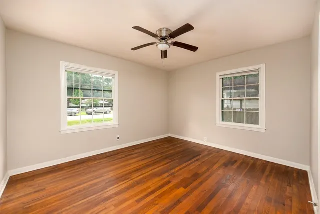 a view of an empty room with wooden floor and a window