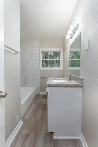 a bathroom with a granite countertop sink and a bathtub