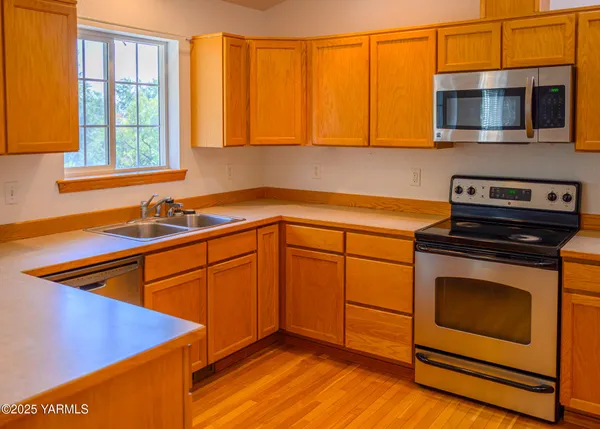 a kitchen with stainless steel appliances granite countertop wooden cabinets a stove a sink and a microwave