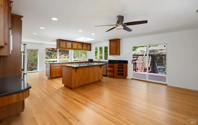 a living room with stainless steel appliances kitchen island granite countertop a stove top oven a sink and a refrigerator