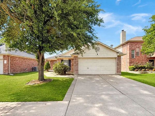 a front view of a house with a yard and a tree