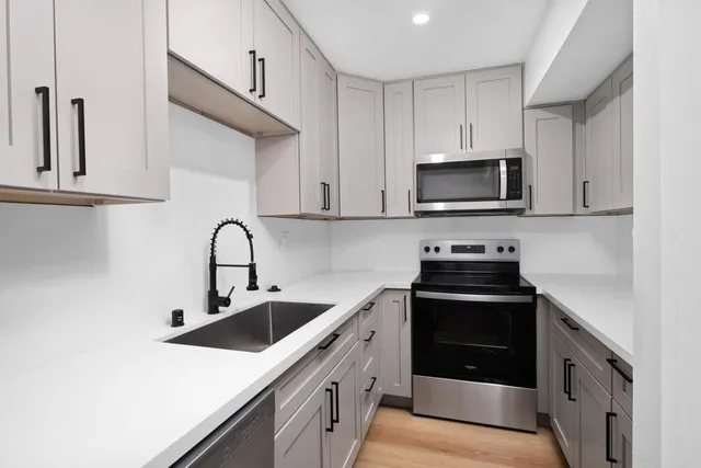 a kitchen with stainless steel appliances granite countertop a sink a stove top oven and refrigerator