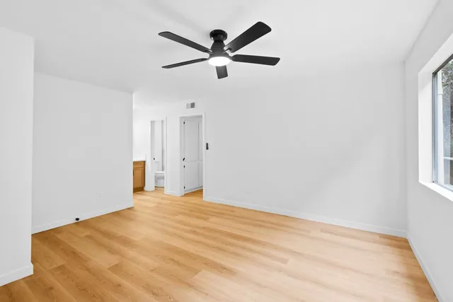 a view of a big room with wooden floor and a ceiling fan