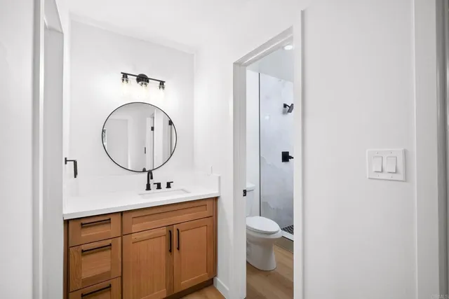 a bathroom with a toilet a sink a mirror and a shower