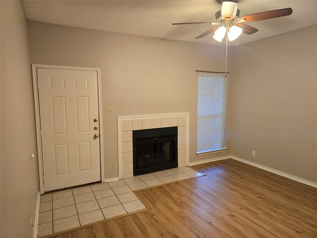 a view of an empty room with a fireplace and a chandelier fan