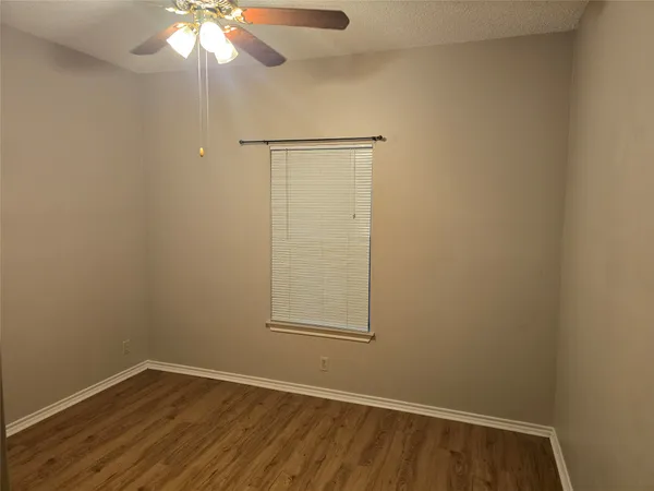an empty room with a hardwood and ceiling fan