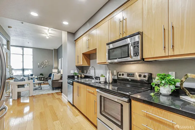 a kitchen with stainless steel appliances granite countertop a sink a stove cabinets counter space and a window