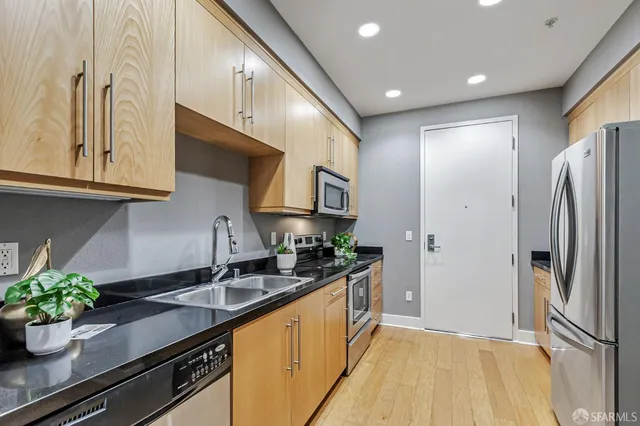 a kitchen with stainless steel appliances granite countertop a sink a stove and a refrigerator
