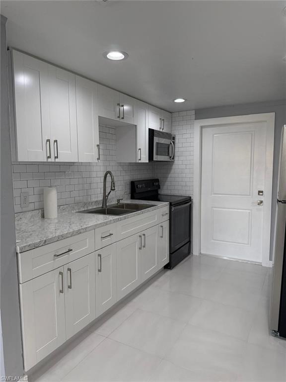 5317 Fleming Street Naples, FL 34113 - Photo 8 of 8 Contemporary kitchen featuring white shaker cabinetry, light-toned countertops, subway tile backsplash, stainless steel appliances, and recessed lighting