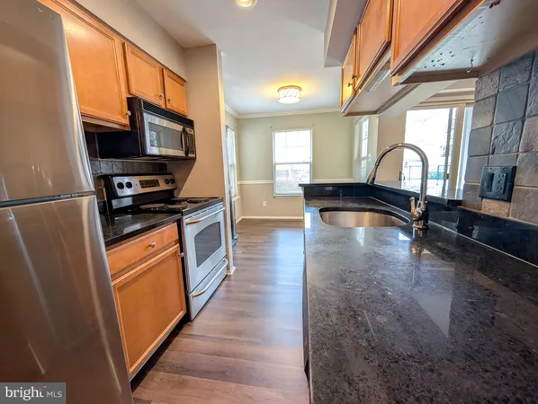 a kitchen with stainless steel appliances granite countertop a refrigerator a stove and a sink with wooden floor