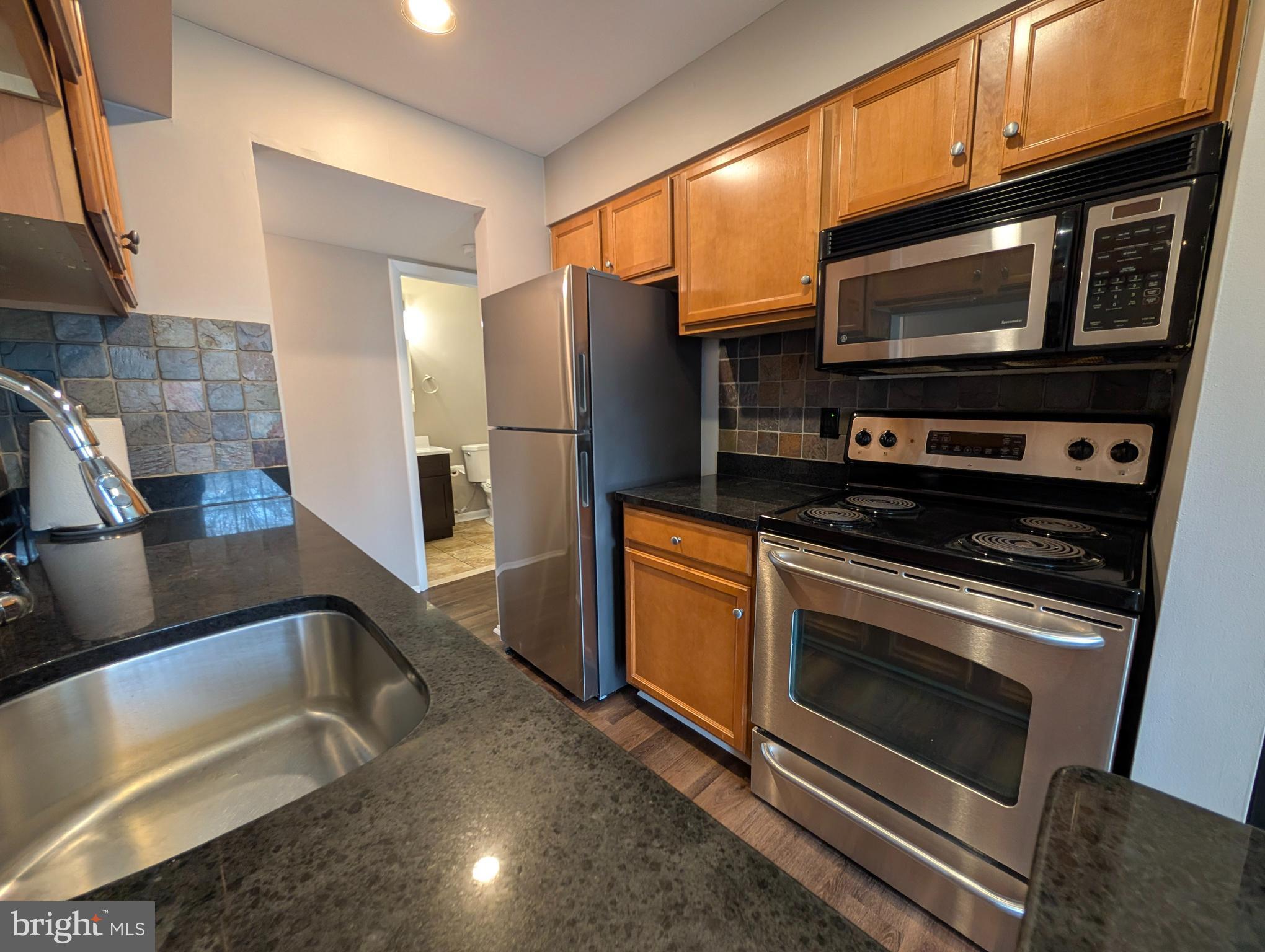 1708 Abercromby Court, Unit 1708B Reston, VA 20190 - Photo 9 of 26 a kitchen with stainless steel appliances granite countertop a stove microwave and refrigerator