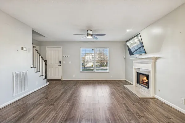 an empty room with fireplace wooden floor and windows