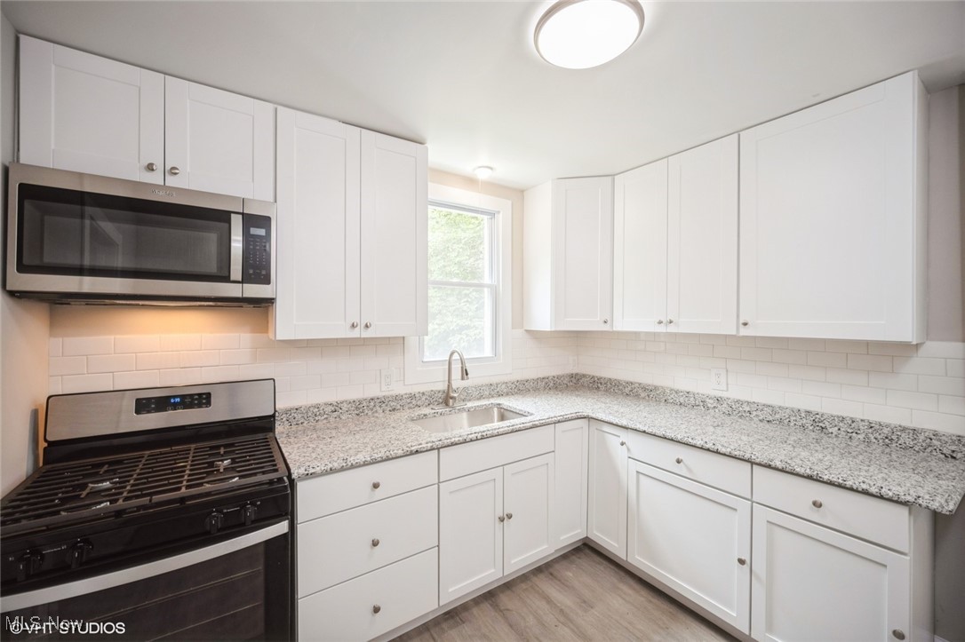 2188 North Taylor Road Cleveland Heights, OH 44112 - Photo 7 of 15 Kitchen featuring appliances with stainless steel finishes, light wood-style floors, and white cabinetry