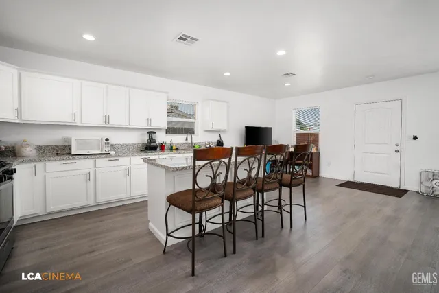 a kitchen with stainless steel appliances kitchen island granite countertop a table chairs sink and cabinets