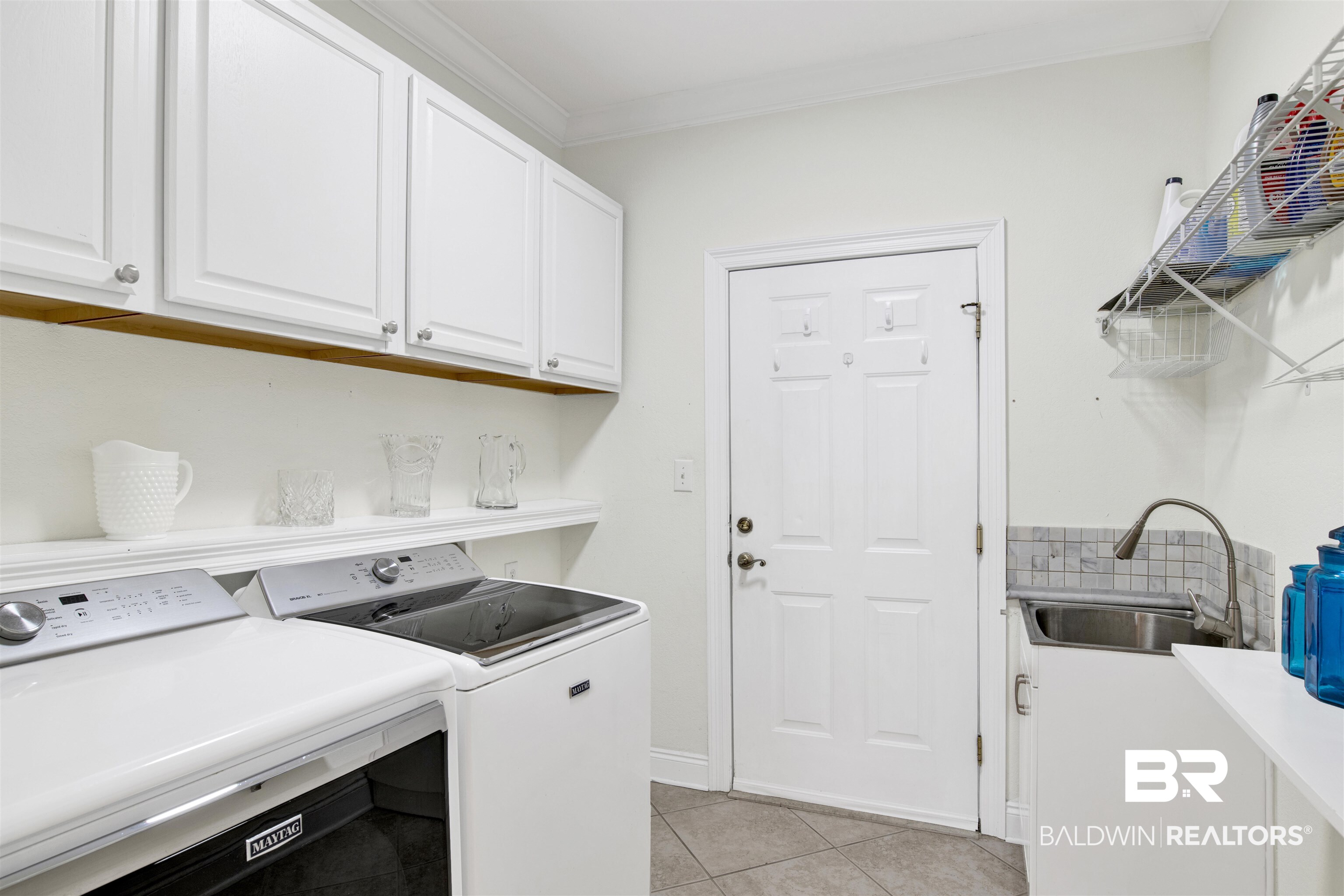 31295 River Road Orange Beach, AL 36561 - Photo 16 of 58 Laundry room with cabinets, washer and clothes dryer, crown molding, sink, and light tile patterned floors