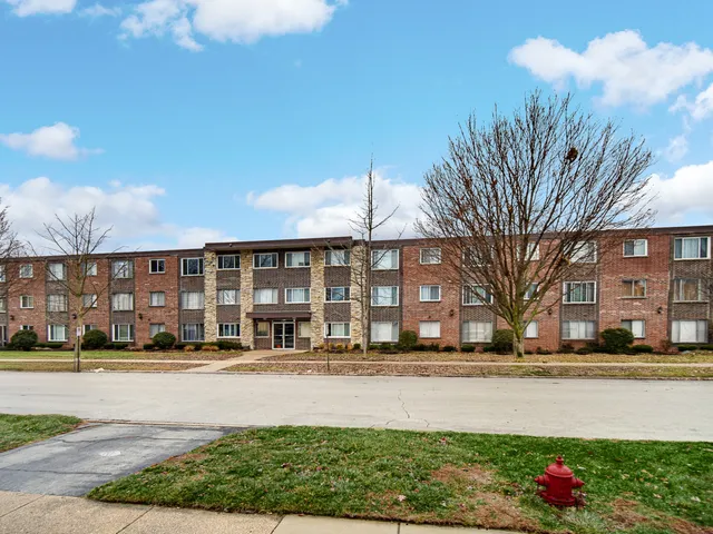 a front view of building with yard and trees around