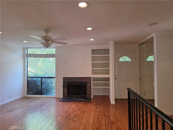 an empty room with wooden floor a fireplace and a window