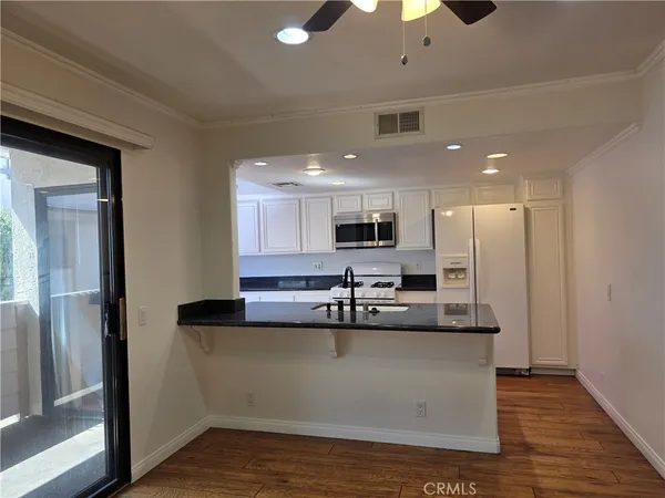 a large kitchen with stainless steel appliances kitchen island a large counter top and a wooden floor