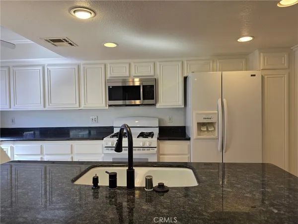 a kitchen with stainless steel appliances granite countertop a sink a stove and a refrigerator