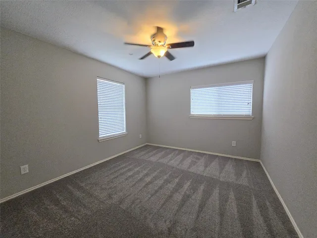 an empty room with a window and a fan