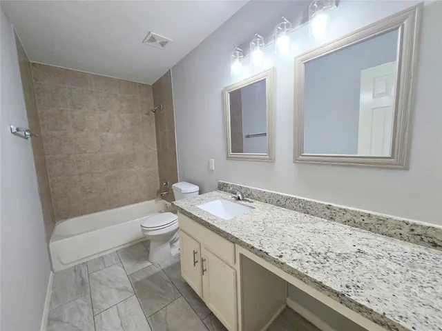 a bathroom with a granite countertop sink a toilet and bathtub