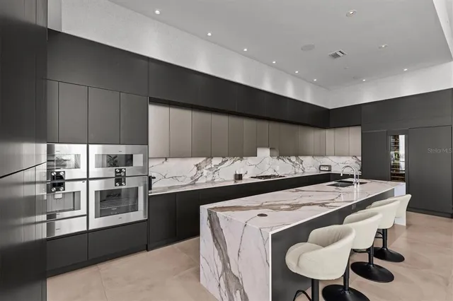 a kitchen with stainless steel appliances kitchen island granite countertop a stove a sink a refrigerator and island with wooden floor