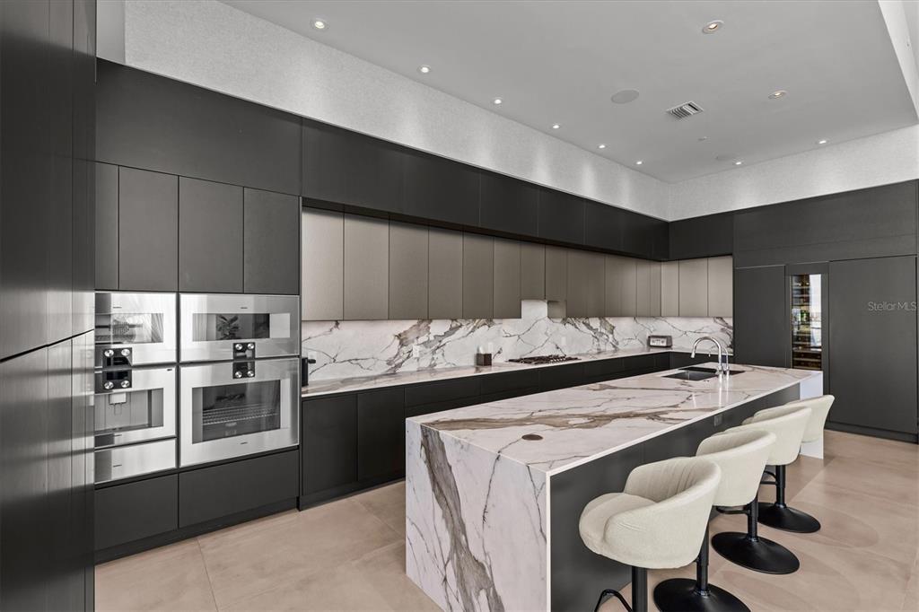 1020 Sunset Point Road, Unit 703 Clearwater, FL 33755 - Photo 10 of 50 a kitchen with stainless steel appliances kitchen island granite countertop a stove a sink a refrigerator and island with wooden floor