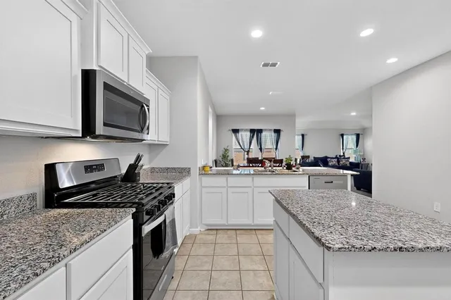 a kitchen with stainless steel appliances granite countertop a sink stove microwave and cabinets