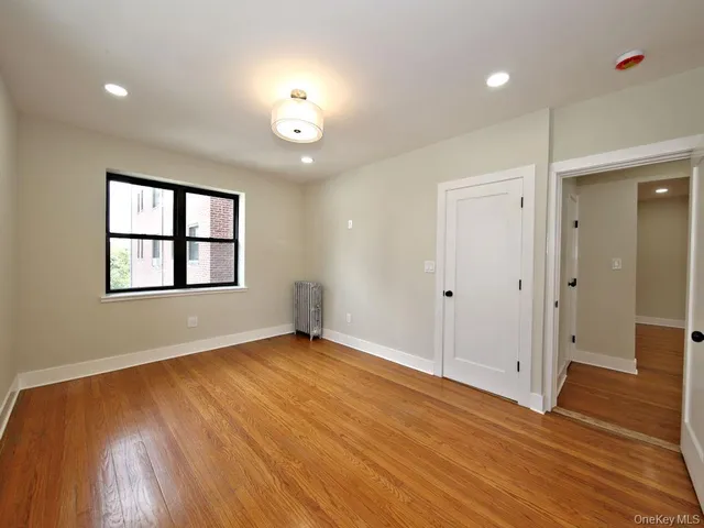 an empty room with wooden floor chandelier and windows