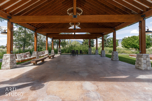 1188 South Old Trappers Loop Road Huntsville, UT 84317 - Photo 6 of 92 Expansive covered patio featuring a wood-beam ceiling, stone-wrapped columns, concrete flooring, and built-in swing seating