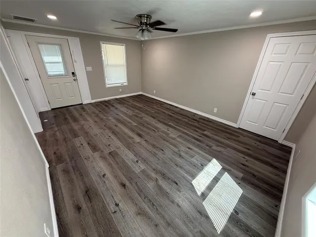 a view of empty room with wooden floor and fan