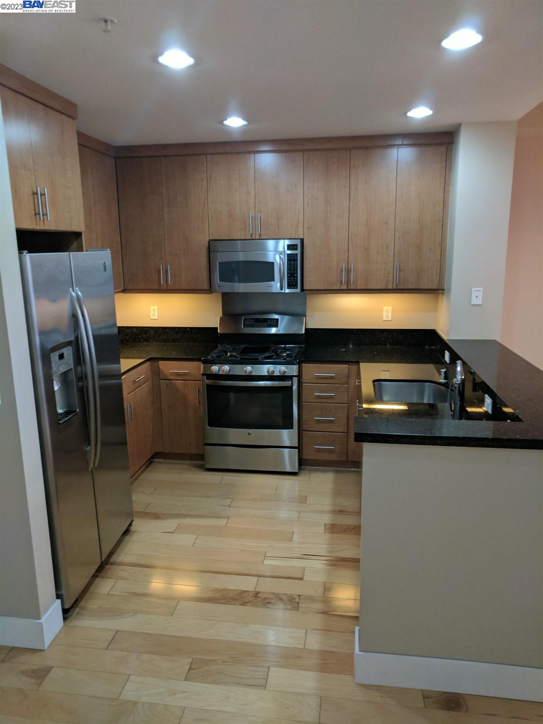 288 3rd Street, Unit 407 Oakland, CA 94607 - Photo 4 of 24 a kitchen with granite countertop stainless steel appliances and wooden cabinets