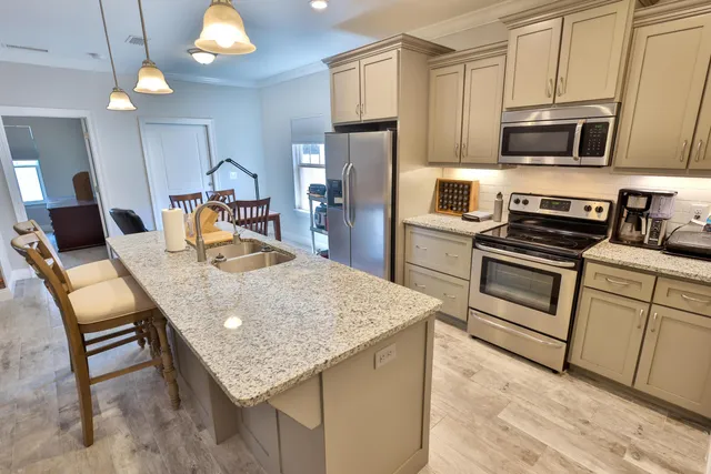 a kitchen with stainless steel appliances granite countertop a kitchen island a stove a sink dishwasher a microwave oven with cabinets and wooden floor