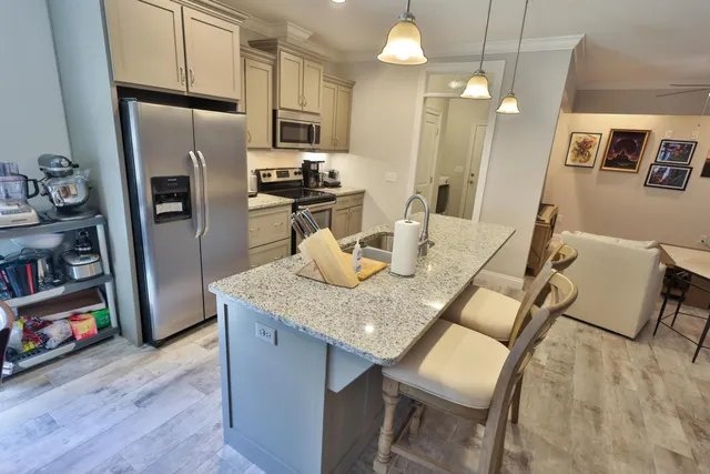 a kitchen with stainless steel appliances granite countertop a kitchen island a stove a refrigerator a dining table and chairs