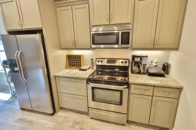 a kitchen with stainless steel appliances granite countertop white cabinets a refrigerator and a stove top oven