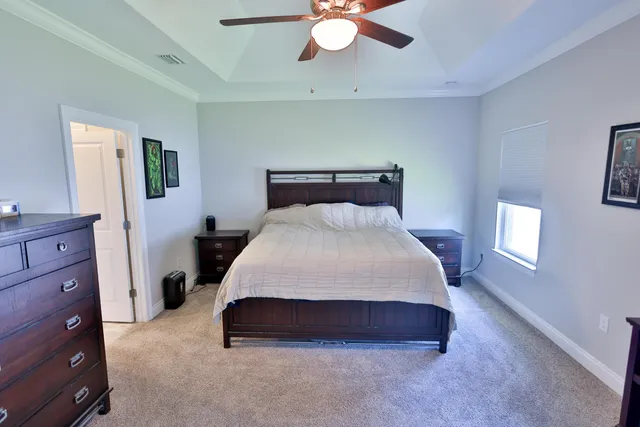 a spacious bedroom with a bed and a chandelier fan