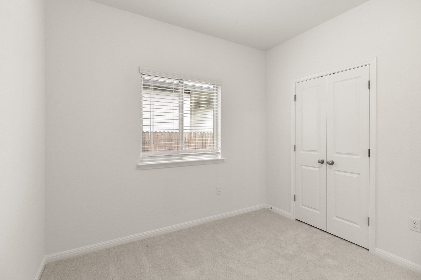 18605 Emu Lane Manor, TX 78653 - Photo 16 of 27 This room offers light-colored carpet, a window with horizontal blinds, and a white bi-fold door