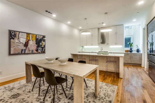 a kitchen with stainless steel appliances kitchen island granite countertop a dining table chairs and a refrigerator