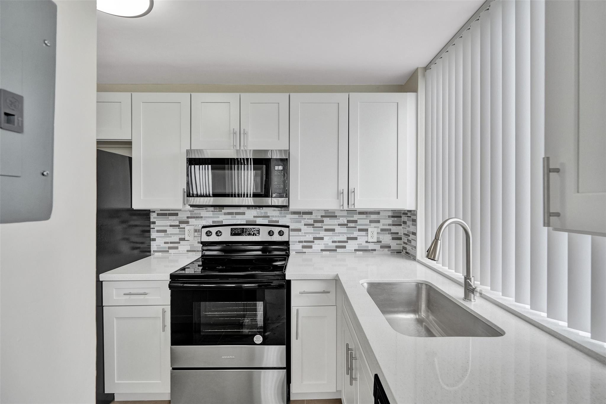 4222 Inverrary Boulevard, Unit 4810 Lauderhill, FL 33319 - Photo 2 of 63 a kitchen with white cabinets a sink and stainless steel appliances