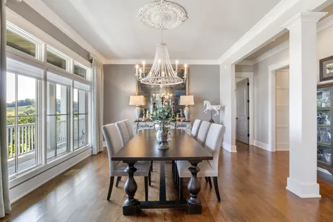 a dining room with furniture large windows and a chandelier