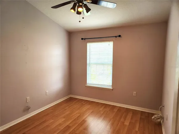 an empty room with a window and a fan