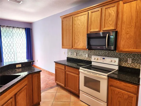 a kitchen with granite countertop wooden cabinets and a stove top oven